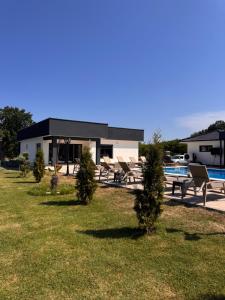a house with a pool and chairs and a building at Villa ZANS in Gradačac