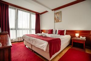 a bedroom with a large bed with a red rug at Hotel Dva Bisera in Ohrid