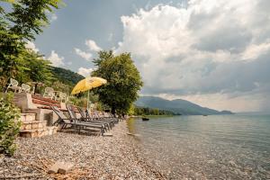 a beach with chairs and an umbrella and water at Hotel Dva Bisera in Ohrid