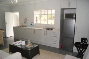 a kitchen with white cabinets and a black refrigerator at Chalet Steenbok in Ladismith