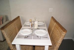 a table with two chairs and a white table with plates at Chalet Steenbok in Ladismith +10 photos
