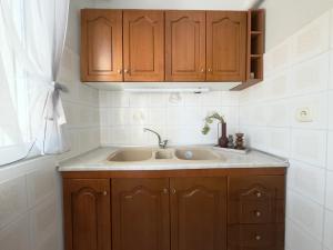 a kitchen with a sink and wooden cabinets at Next to the Beach Apartments , Delta Hospitality in Ofrínion +50 photos