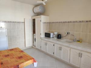 a kitchen with white cabinets and a sink and a refrigerator at Dar Pikhasa in Saïdia