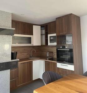 a kitchen with wooden cabinets and a table with chairs at Villa ZANS in Gradačac