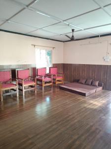 a room with red chairs and a bed on a wooden floor at Ira's Abode in Dibrugarh