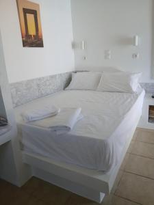 a white bed with white sheets and pillows on it at Studio Angelika in Glinado Naxos