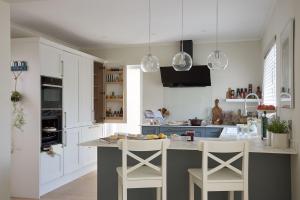 a kitchen with white cabinets and a island with two stools at Meadow Drive in Bembridge +30 photos