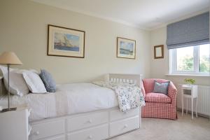 a bedroom with a white bed and a chair at Meadow Drive in Bembridge