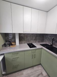 a kitchen with green and white cabinets and a sink at Taikos apartamentai in Utena