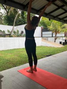 a woman doing a yoga pose on a red mat at Ocean Life Ayurvedic Villa in Talalla South