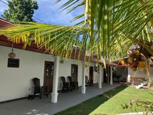 a porch of a house with chairs and a palm tree at Ocean Life Ayurvedic Villa in Talalla South