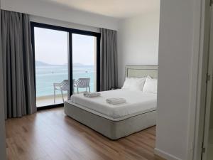 a bedroom with a bed and a view of the ocean at Swiss Rivage Hotel in Vlorë