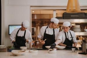 a group of three chefs preparing food in a kitchen at Boutique Hotels MANNA & Blue in Nijmegen