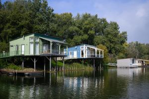 two houses on a dock on a body of water at Olivér cölöpház in Tiszafüred