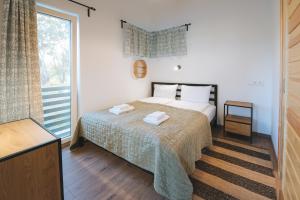 a bedroom with a bed with two towels on it at Olivér cölöpház in Tiszafüred