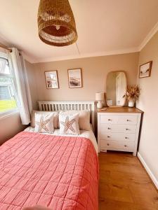 a bedroom with a bed and a dresser and a mirror at The Coastal Cosy, St Merryn, Padstow in Saint Merryn