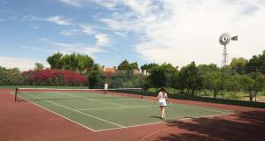two women playing tennis on a tennis court at Quinta Da Praia Das Fontes in Alcochete