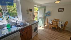 a kitchen with a sink and a washing machine at Driftwood in Porthtowan