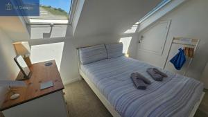 a small bedroom with a bed with slippers on it at Driftwood in Porthtowan