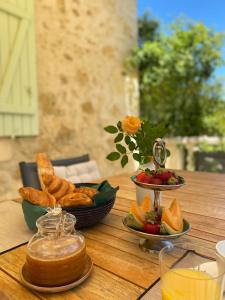 a table with bread and fruit and a bowl of food at La Bordeneuve - Chambre d'hôtes in Auch