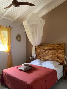 a bedroom with a red bed with a ceiling fan at Chez BIBI in Grand-Bourg