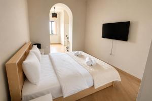 a bedroom with a white bed with a flat screen tv at Miassine Boutique Hotel in Gyumri