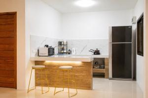 a kitchen with a counter with stools and a refrigerator at Villa Archie INCREDIBLE Sea View second fl in Ko Phangan +13 photos