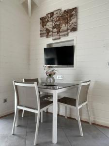 a white table with two chairs and a television on a wall at Chez BIBI in Grand-Bourg