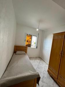 a small bedroom with a bed and a window at Dar l Bihar in Al Hoceïma
