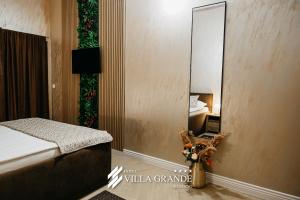 a bedroom with a mirror and a bed and a vase of flowers at Villa Grande Terrace Jacuzzi Suite in Bugojno
