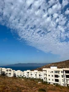 a row of apartment buildings on a hill with a cloudy sky at Dar l Bihar in Al Hoceïma