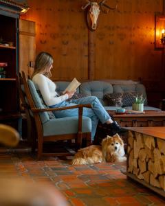a woman sitting in a chair reading a book next to a dog at GRETI - Alpine Boutique Hotel mit Alpentherme Eintritt, reichhaltigem Frühstück, Sauna in Bad Hofgastein +92 photos