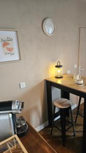 a table with a stool and a clock on the wall at Ker Bellevue, chambre Dinan in Lanvallay +1 photo