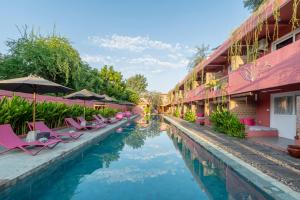 a pool with chairs and umbrellas next to a hotel at PinkCoco Gili Trawangan - Constant Surprises - for Cool Adults Only in Gili Trawangan