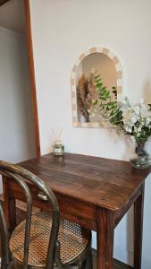 a wooden table with a vase of flowers and a mirror at Ker Bellevue, chambre Dinan in Lanvallay
