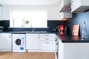 a kitchen with white cabinets and a washer and dryer at Carley's House - Macduff Seaside Escape in Macduff +19 photos