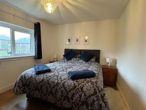 a bedroom with a bed with blue pillows on it at Carley's House - Macduff Seaside Escape in Macduff