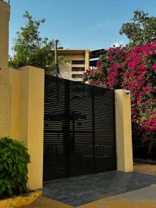 a black gate in front of a building with pink flowers at Hamsun Shahrah-e-Faisal Extension in Karachi