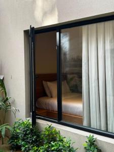 a glass window with a bed in a room at Hamsun Shahrah-e-Faisal Extension in Karachi
