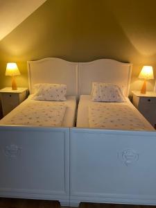 two white beds in a room with two lamps at Haus König in Kirchbach