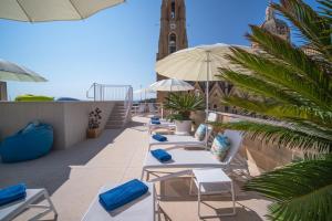 a row of beach chairs and umbrellas on a balcony at The White Knight Premium Boutique Hotel in Għajnsielem