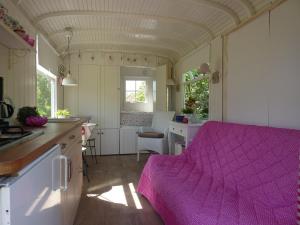 eine Küche mit einem rosa Bett in einem winzigen Haus in der Unterkunft pipowagen Blagour gelegen aan waterbron in Lachapelle-Auzac