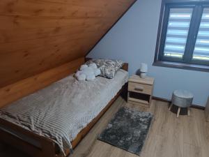 a bedroom with a bed with a teddy bear on it at Jesionowy Zakątek domki z balią blisko jeziora in Piasutno +39 photos