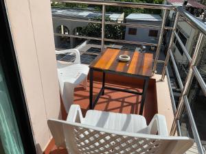 a balcony with a wooden table and white chairs at Smile Home in Patong Beach