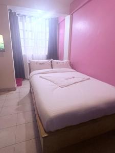 ein Bett in einem Zimmer mit einer rosa Wand in der Unterkunft Spass Hotel in Eldoret