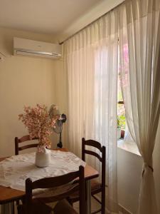 a dining room table with a vase of flowers and a window at La Casa di Nonna in Qeparo +51 photos