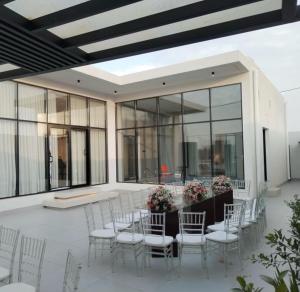a patio with white chairs and a table with flowers at شاليه اغصان الباحة in Al Baha