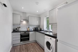a kitchen with white cabinets and a washer and dryer at K Suites - Walsingham Close in Hatfield +3 photos