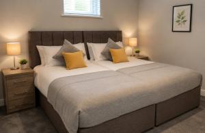 a bedroom with a large bed with yellow pillows at K Suites - Walsingham Close in Hatfield
