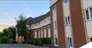 a red brick building with a tree in front of it at K Suites - Walsingham Close in Hatfield